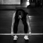 A woman preparing to lift a barbell in a gym, showcasing strength and focus.