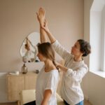 A therapist assists a woman with arm stretching during a session in a calming indoor setting.