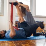 Man in rehabilitation exercises with a trainer, focusing on prosthetic leg recovery.